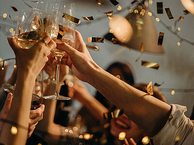 En gruppe til fest der skåler i champagne mens guld konfetti daler