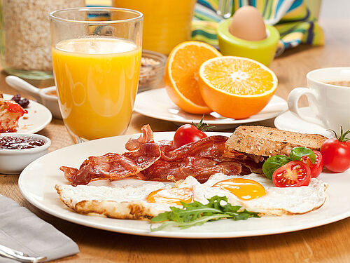 Brunch-Frühstück mit Spiegeleiern, Speck und Saft